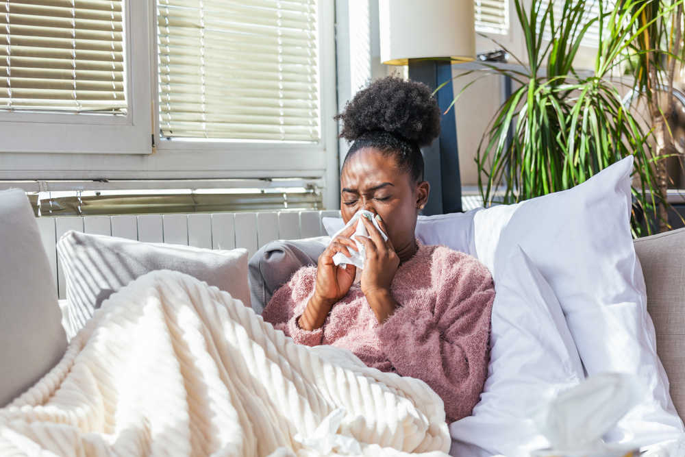sick woman experiencing sinus issues blowing her nose